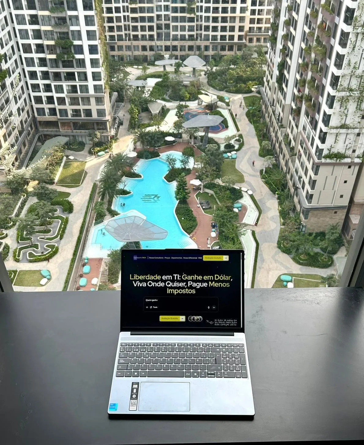 Notebook aberto no site da Passaporte Tech, numa varanda com vista para prédios e piscina